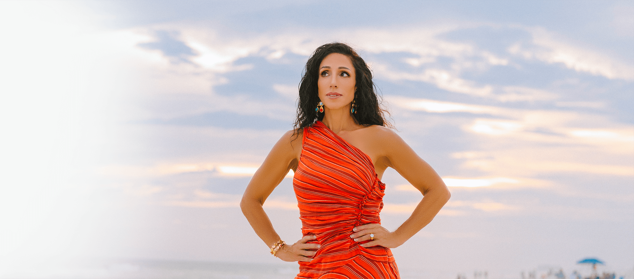 Dr. Michelle in a red dress sitting on the beach